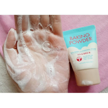 Hand with soap suds and a bottle of baking powder on a pink background.Iceland