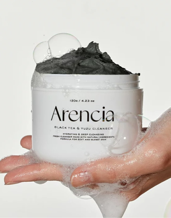 Arencia black tea and yuzu cleanser texture with a hand holding it against a white background