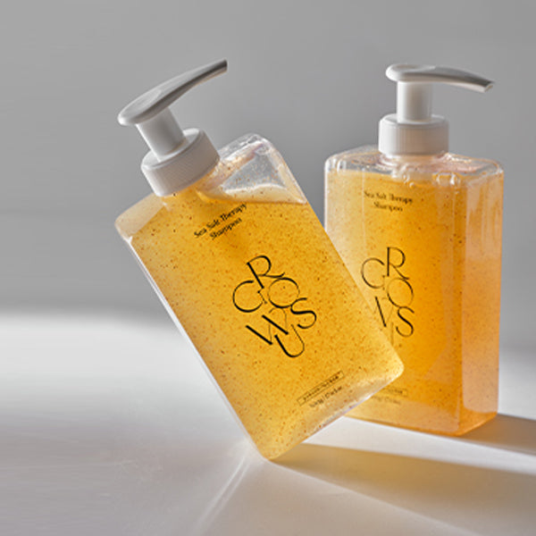 Two bottles of orange liquid soap with pump dispensers on a gray background