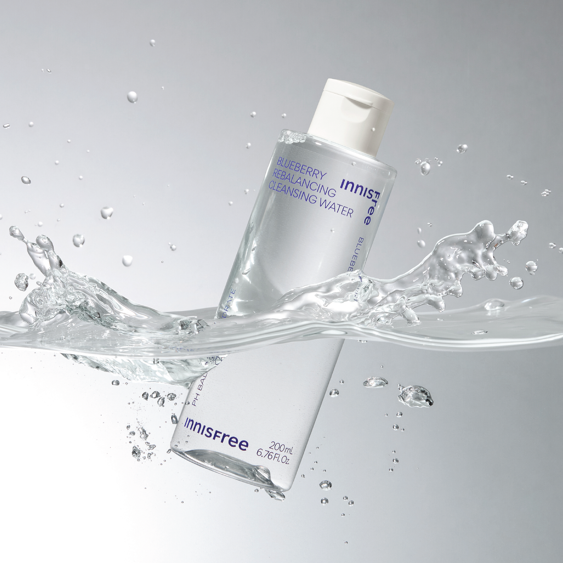Two bottles of Innisfree Blueberry Balancing Cleansing Water with water splashes on a gray background
