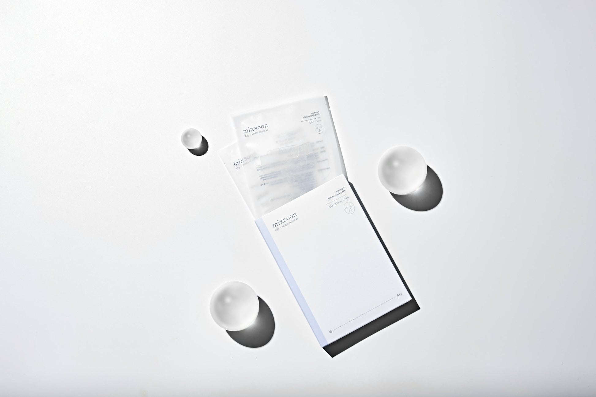 Two white face masks on a light gray background with mask liquid dripping